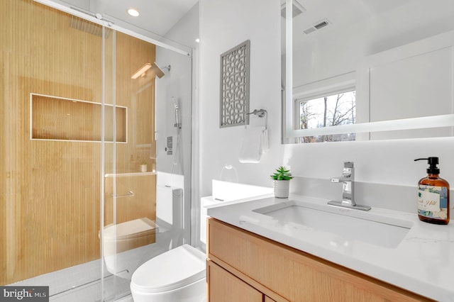 bathroom with toilet, vanity, and a shower with shower door