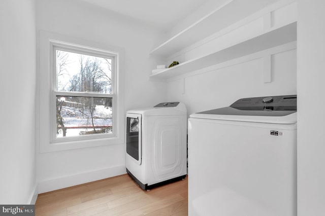 laundry room featuring washing machine and clothes dryer and light hardwood / wood-style flooring