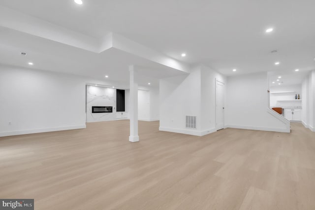 basement featuring a premium fireplace and light hardwood / wood-style floors