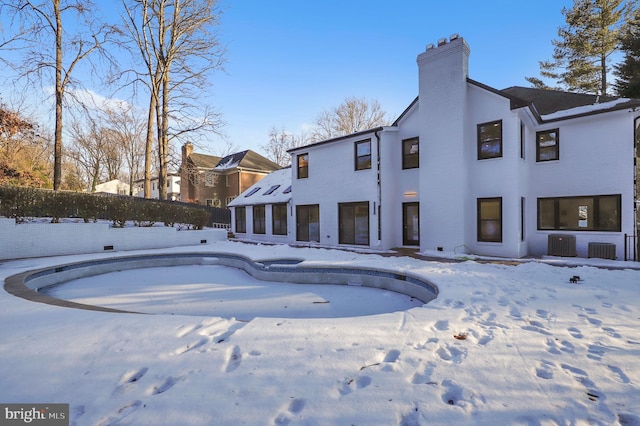 snow covered back of property featuring central AC