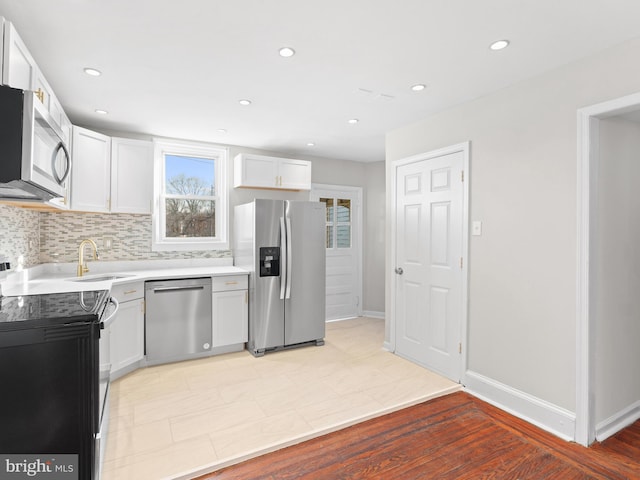 kitchen featuring stainless steel appliances, white cabinetry, tasteful backsplash, and sink