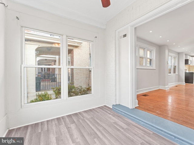 empty room featuring a wealth of natural light, ceiling fan, and light hardwood / wood-style floors