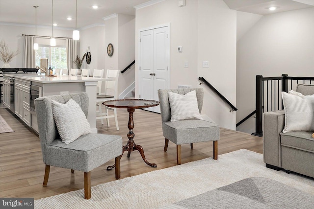 living area featuring light wood-type flooring and ornamental molding