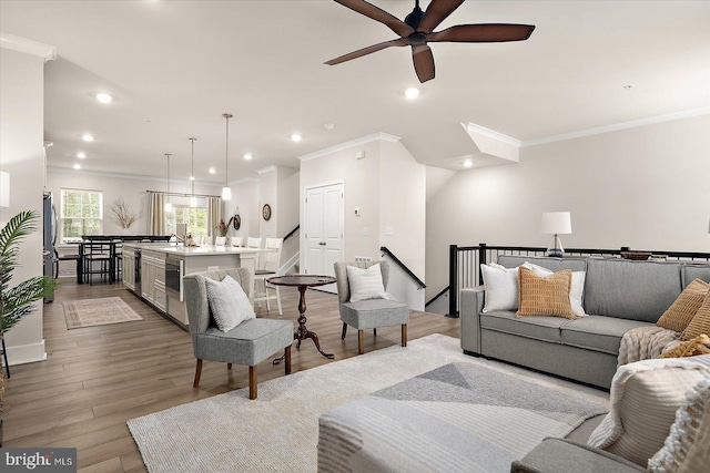 living room featuring light hardwood / wood-style flooring, ceiling fan, and crown molding