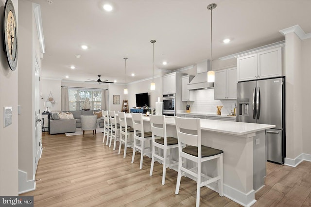 kitchen with appliances with stainless steel finishes, custom exhaust hood, ceiling fan, white cabinets, and hanging light fixtures