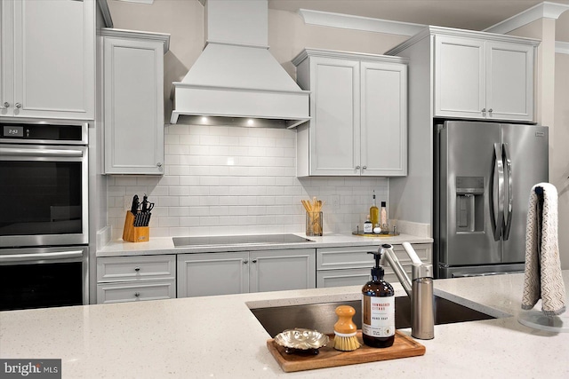 kitchen with white cabinets, appliances with stainless steel finishes, and premium range hood