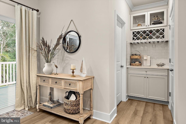 bar featuring decorative backsplash, light wood-type flooring, and white cabinetry