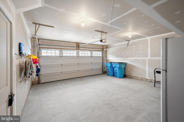 garage featuring white refrigerator and a garage door opener