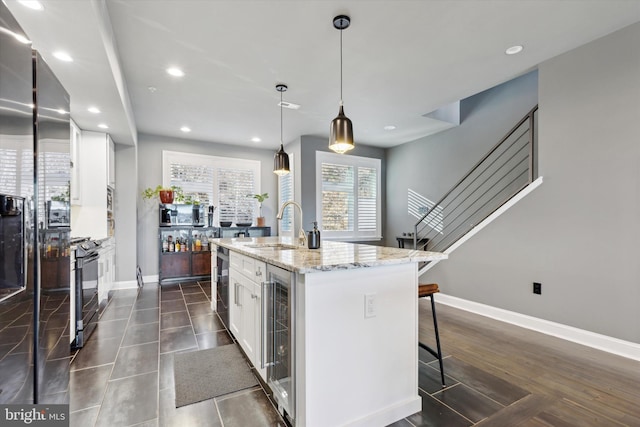 kitchen with pendant lighting, sink, an island with sink, dark hardwood / wood-style flooring, and white cabinetry