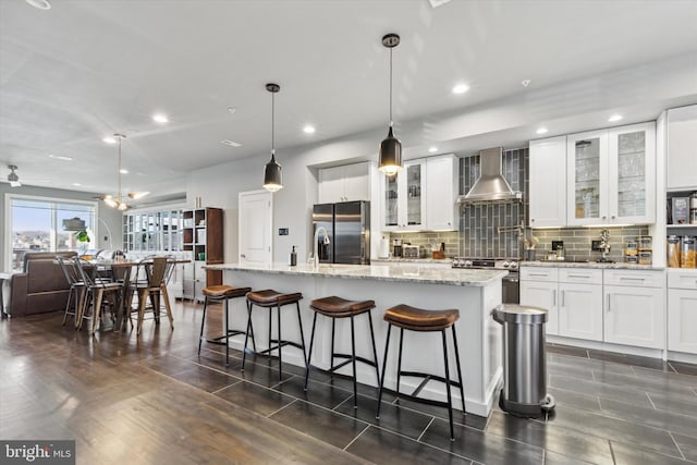 kitchen featuring white cabinets, wall chimney exhaust hood, decorative light fixtures, dark hardwood / wood-style flooring, and stainless steel appliances