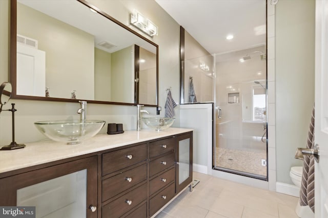 bathroom featuring toilet, a shower with door, vanity, and tile patterned flooring