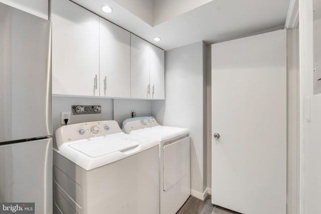 clothes washing area with separate washer and dryer, dark hardwood / wood-style flooring, and cabinets