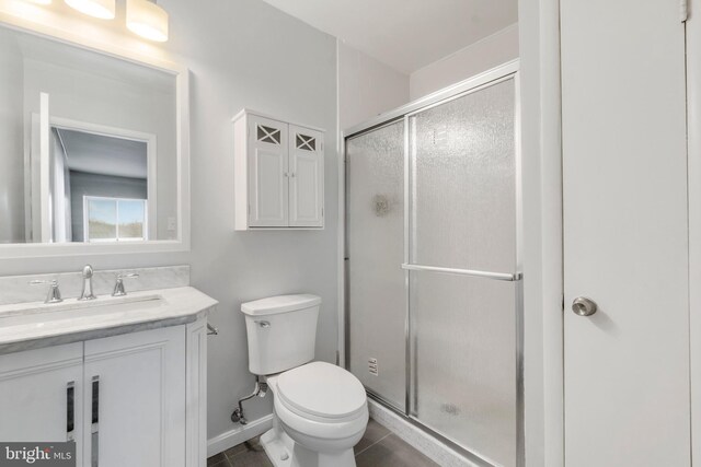 bathroom featuring tile patterned flooring, vanity, toilet, and a shower with door