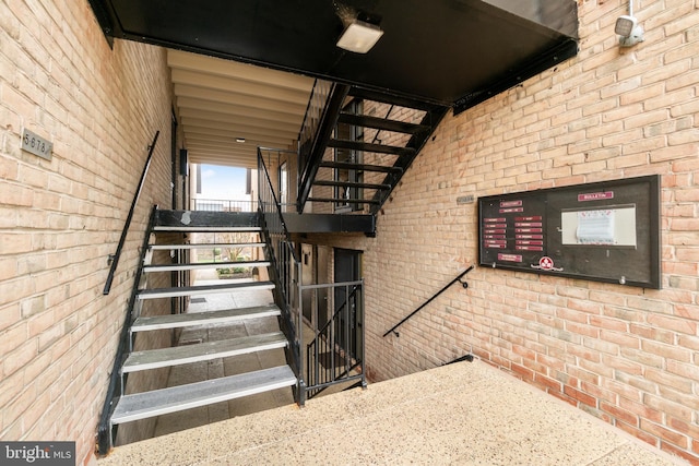 stairway featuring brick wall