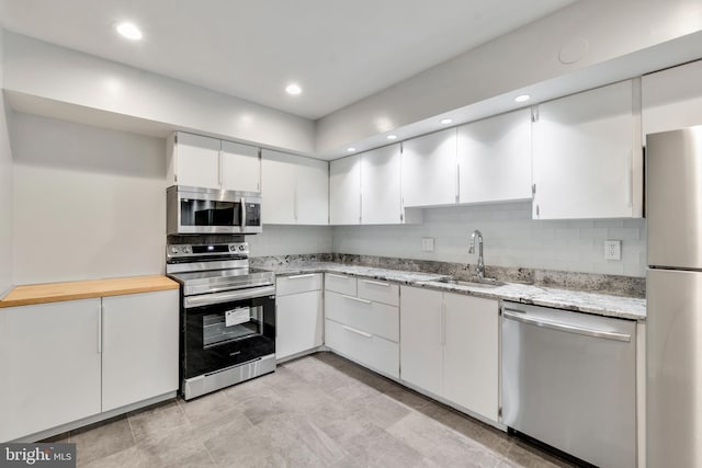 kitchen featuring decorative backsplash, white cabinetry, sink, and appliances with stainless steel finishes