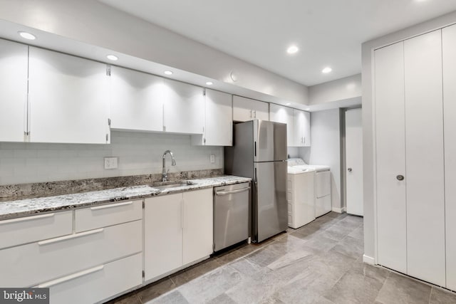 kitchen with appliances with stainless steel finishes, tasteful backsplash, sink, separate washer and dryer, and white cabinets