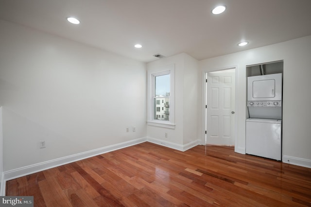 unfurnished room featuring wood-type flooring and stacked washer and clothes dryer