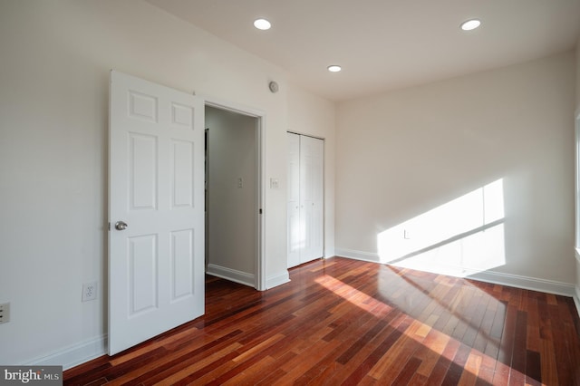 unfurnished bedroom with a closet and dark wood-type flooring