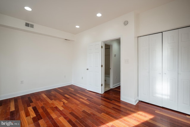 unfurnished bedroom featuring a closet and dark wood-type flooring