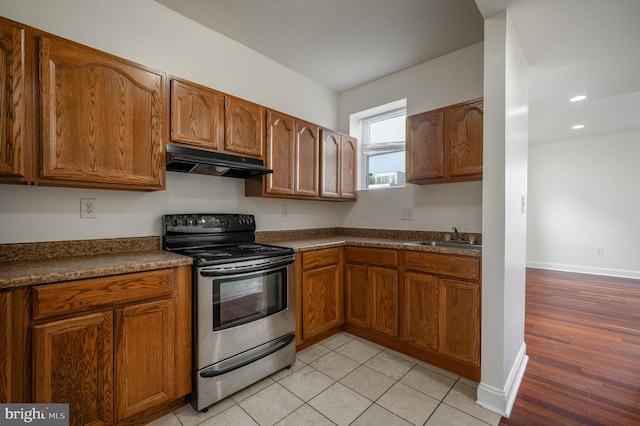 kitchen with light tile patterned flooring, sink, and stainless steel range with electric cooktop