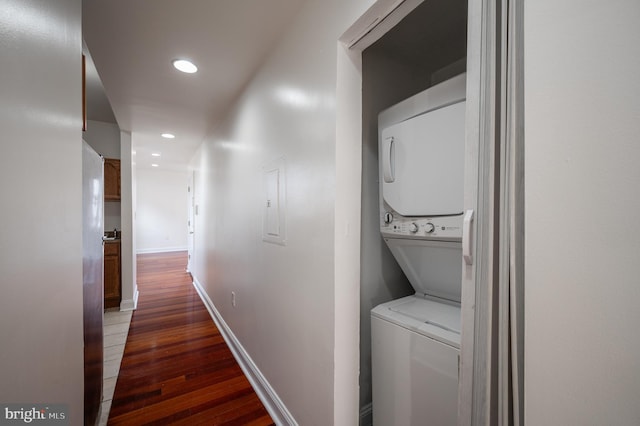 clothes washing area featuring dark hardwood / wood-style flooring and stacked washer and dryer