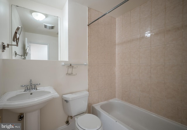 bathroom featuring toilet and tiled shower / bath