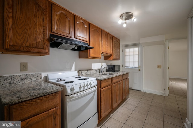 kitchen with stone counters, light tile patterned floors, white range oven, and sink