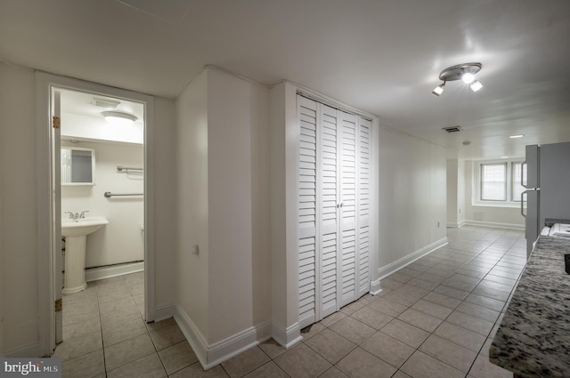 hall featuring sink and light tile patterned flooring