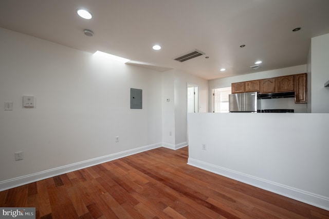 interior space featuring electric panel, hardwood / wood-style flooring, and stainless steel refrigerator