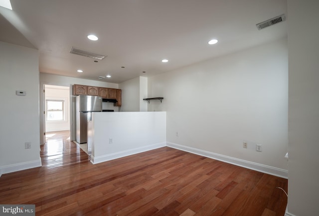 kitchen with kitchen peninsula, stainless steel fridge, and dark wood-type flooring