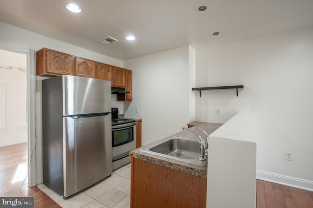 kitchen with light wood-type flooring, stainless steel appliances, and sink