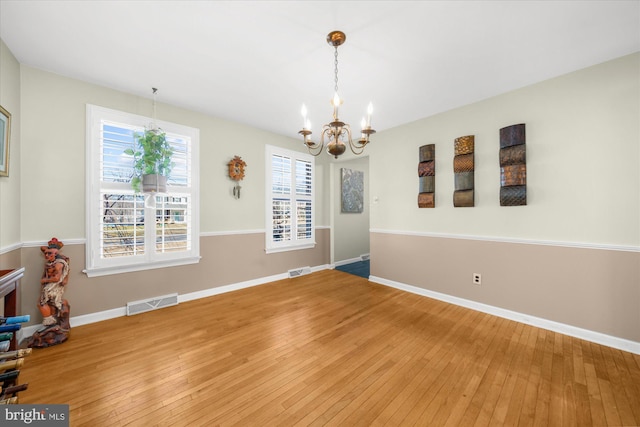 unfurnished dining area with light wood-type flooring, baseboards, and a notable chandelier