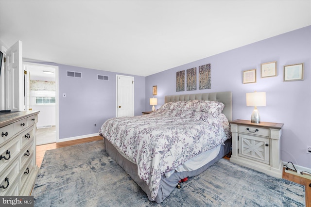 bedroom featuring wood finished floors, visible vents, and baseboards