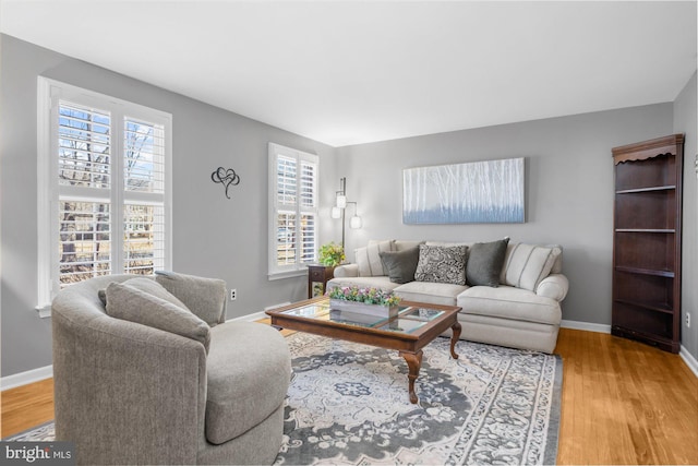 living room with light wood-style floors, baseboards, and a wealth of natural light