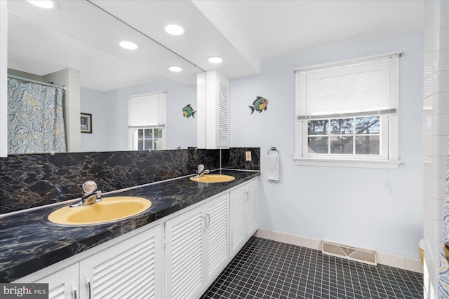 bathroom with tile patterned flooring, visible vents, a sink, and decorative backsplash