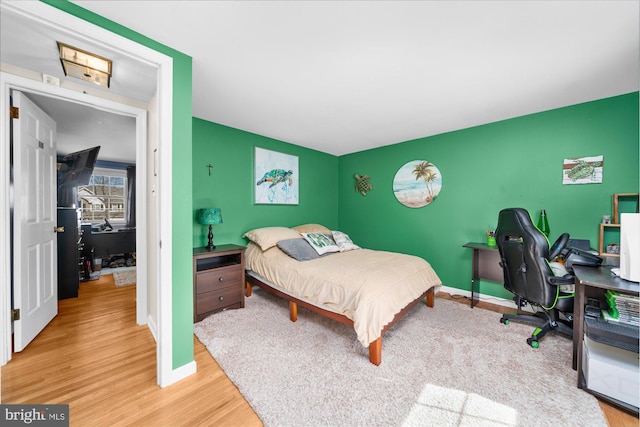 bedroom with an accent wall, baseboards, and wood finished floors