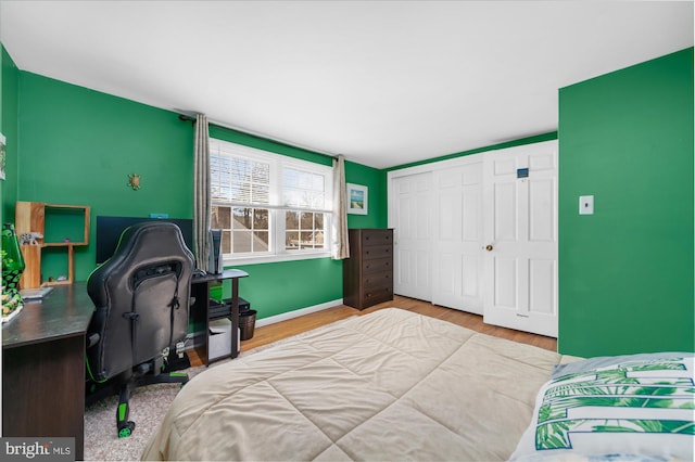 bedroom with a closet, baseboards, and wood finished floors