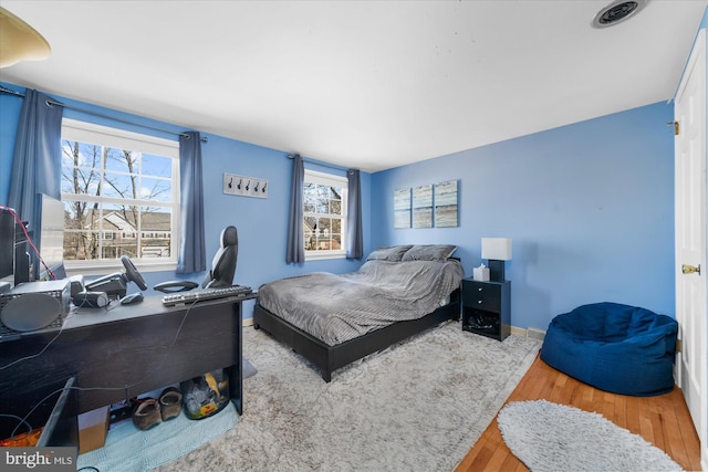 bedroom featuring multiple windows, wood finished floors, and baseboards