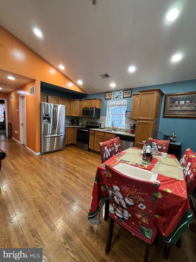 kitchen featuring sink, light hardwood / wood-style flooring, appliances with stainless steel finishes, and vaulted ceiling