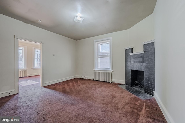 unfurnished living room with dark carpet, radiator heating unit, and a wealth of natural light