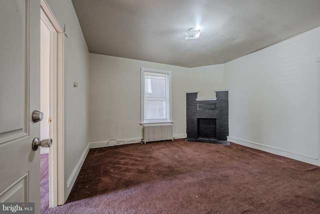 unfurnished living room with carpet flooring, radiator, and a fireplace