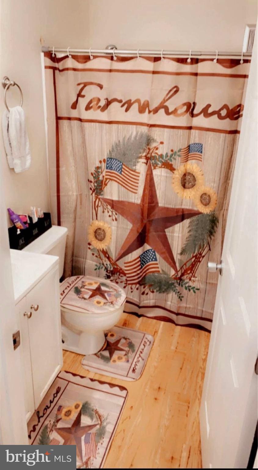 bathroom featuring curtained shower, hardwood / wood-style floors, vanity, and toilet