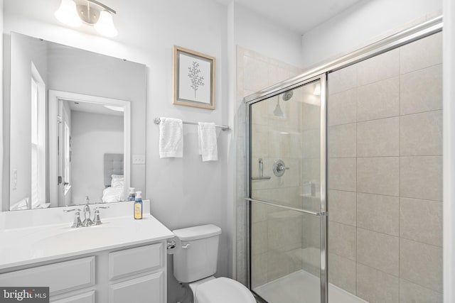 bathroom with a shower with shower door, vanity, and toilet