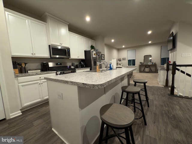 kitchen featuring white cabinetry, sink, stainless steel appliances, and a center island with sink