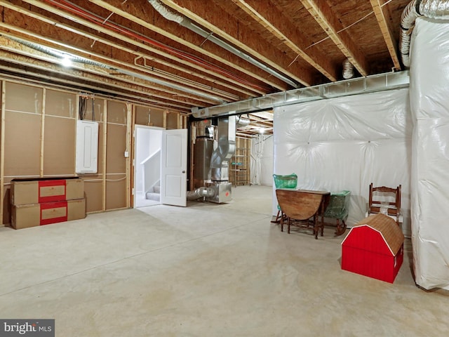 basement featuring electric panel and heating unit