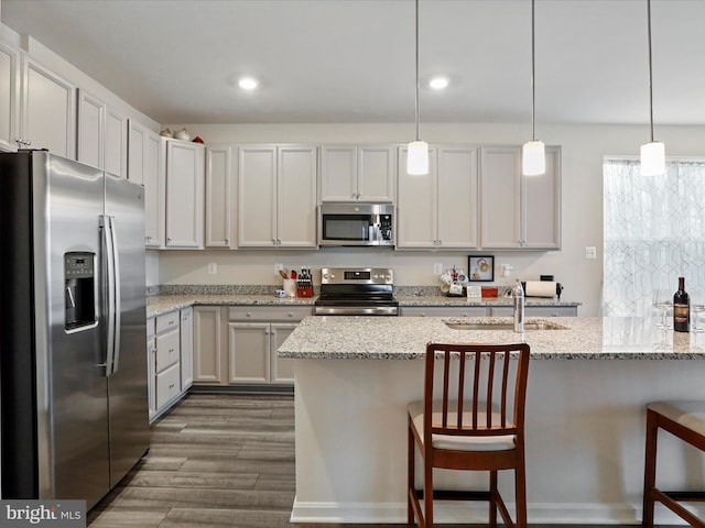 kitchen featuring a breakfast bar area, dark wood-type flooring, hanging light fixtures, and appliances with stainless steel finishes