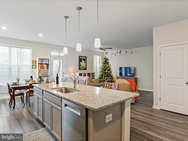 kitchen with sink, hanging light fixtures, stainless steel dishwasher, ceiling fan, and an island with sink