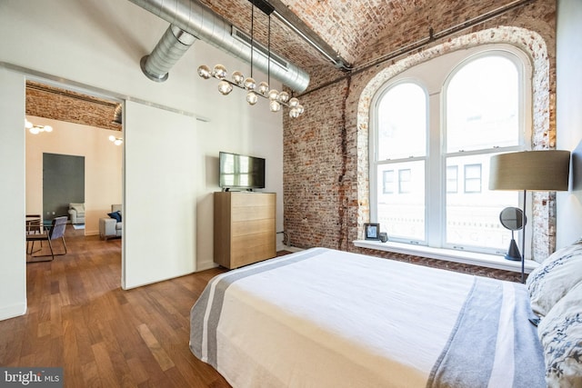 bedroom with a high ceiling, brick ceiling, brick wall, and wood-type flooring