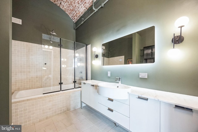 bathroom with bath / shower combo with glass door, brick ceiling, tile patterned floors, and vanity