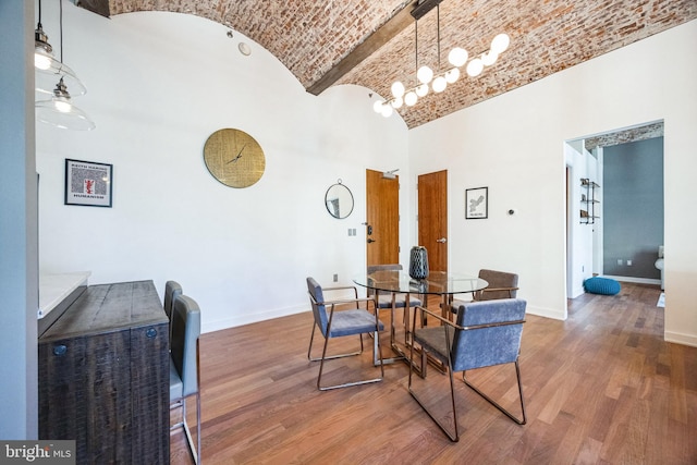 dining room featuring lofted ceiling, hardwood / wood-style flooring, and brick ceiling